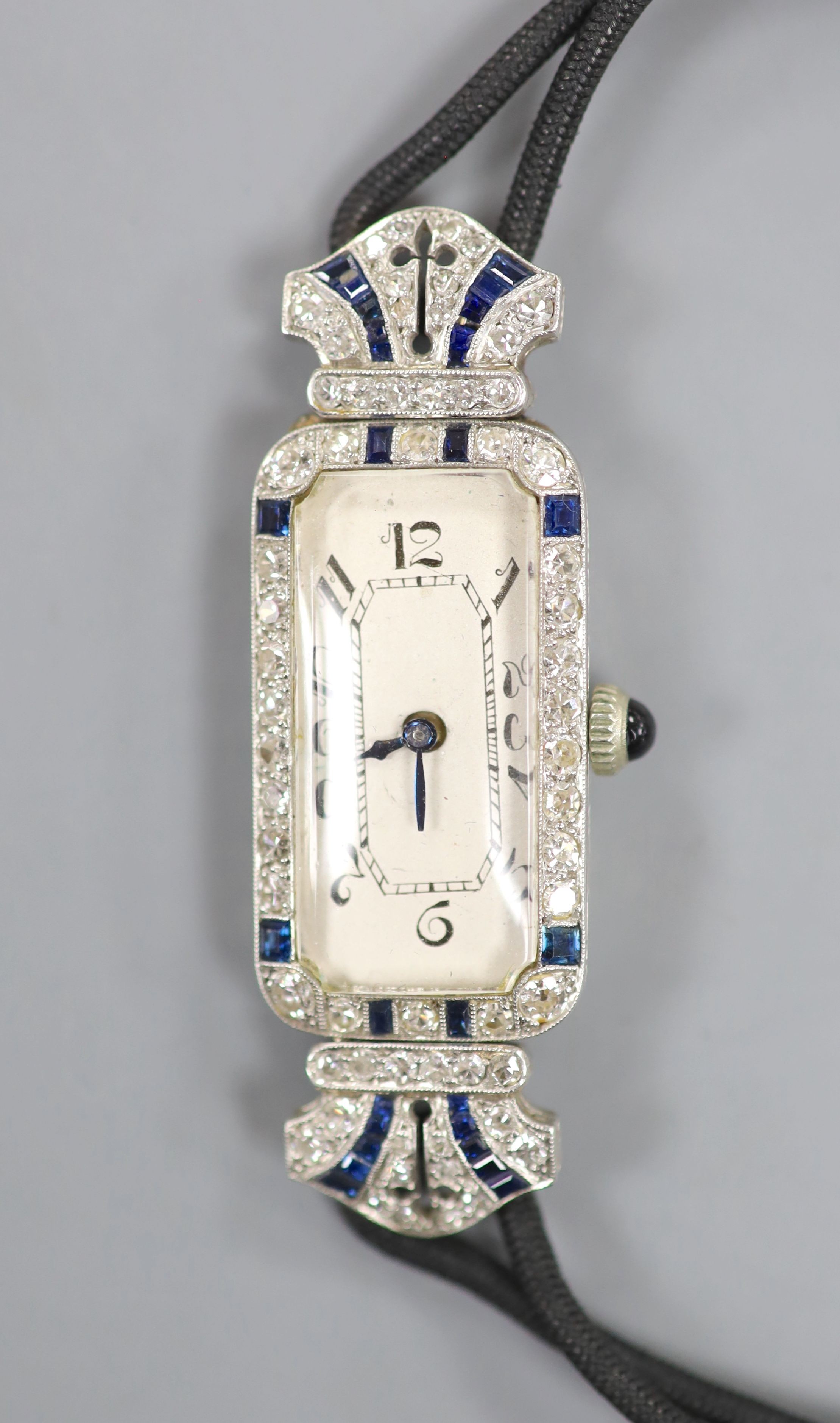 A lady's 1920's/1930's yellow and white metal, synthetic? sapphire and diamond set cocktail watch, now with battery operated movement, on a twin strand fabric strap, case diameter 15mm, gross weight 17.3 grams.